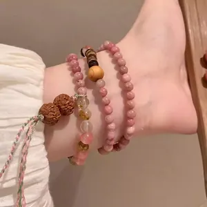 Detail view of multi-layered anklet featuring pink stones and woven cord on ankle