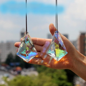 Close-up of hand holding two large K9 crystal prisms with colorful rainbow reflections