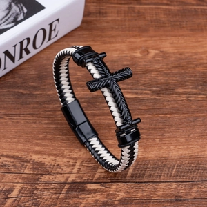 Men's braided leather bracelet with black cross and magnetic clasp on dark wood