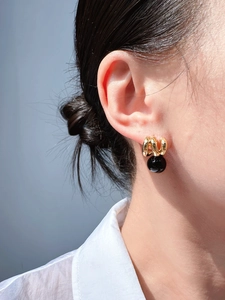 Detail of vintage gold earrings with black agate beads on model ear close-up