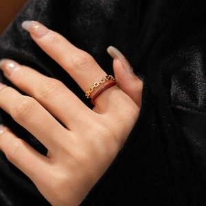 Close-up of vintage golden chain ring and red enamel band set on female hand