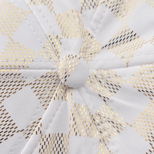Macro shot of white fabric with gold foil grid print and detailed stitching on a baseball cap