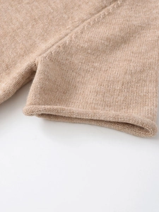 Detailed macro shot of a camel knit top showing soft wool texture and rolled edge hem