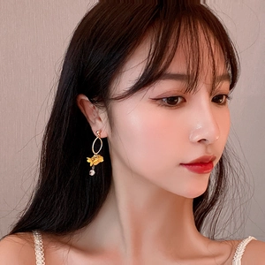 Elegant long gold earrings featuring large oval loops and yellow floral pendant charms