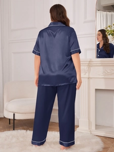 Navy blue satin pajama set with short-sleeved top and trousers featuring white piped edges