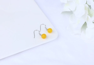 Detail of yellow agate drop earrings with silver hooks on an elegant white tray