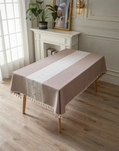 Detailed close-up of beige jacquard Christmas reindeer tablecloth with elegant white tassels