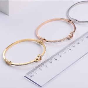 Three-color heart-shaped stainless steel bracelets shown with a measurement scale for size
