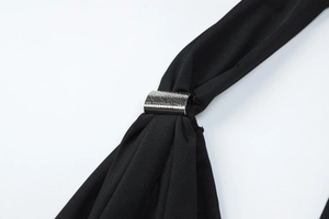 Detailed macro view of hammered silver buckle on a sleek black backless jumpsuit