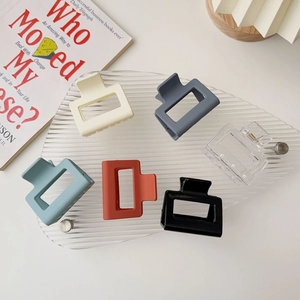 Flat lay of square matte hair claws in various candy colors on a clear acrylic board