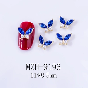 Macro detail of alloy butterfly nail charms with blue crystals and pearls for DIY nail art