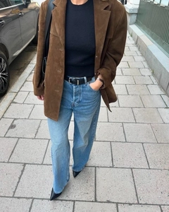 Street style view of a brown suede blazer paired with light blue jeans and black shoes