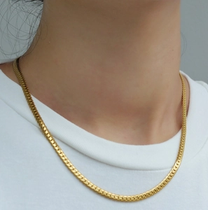 Close-up of a sleek golden titanium flat snake chain necklace on a model's neck