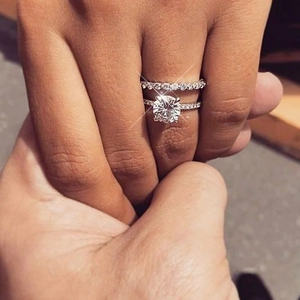 Elegant six-prong moissanite bridal ring set with matching pave wedding bands on hand