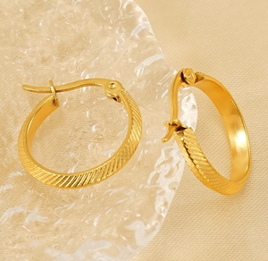 Macro view of gold plated stainless steel hoop earrings with textured diagonal stripes