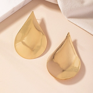 Detailed view of golden teardrop earrings with a textured brushed metal finish surface