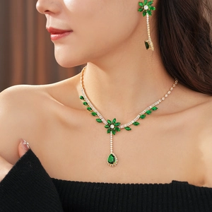 Close-up of gold flower necklace and earrings set featuring sparkling green zircons