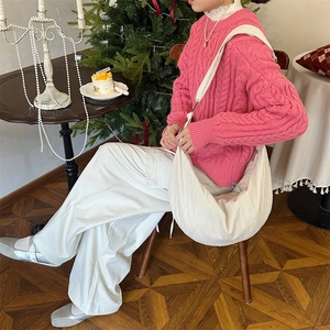 Detail of pink knitted sweater texture paired with a crescent bag and winter festive decor