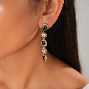 Detail view of vintage gold-tone earrings with black and clear crystals on a model