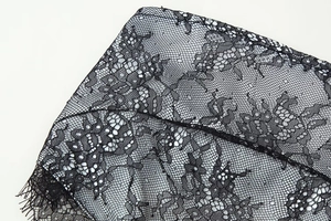 Macro shot of delicate floral lace pattern with fine mesh texture on black satin dress
