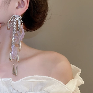 Close-up of dangling silver tassel earrings with purple petals and sparkling rhinestones