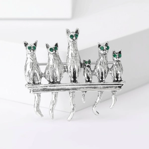 Detail of vintage silver cat brooch with green gem eyes and textured alloy finish