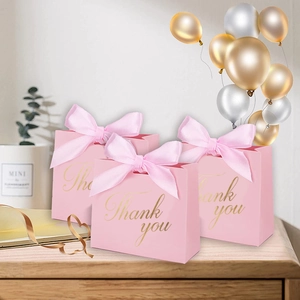 Détail de sacs cadeaux roses avec texte doré Thank You et rubans en soie assortis