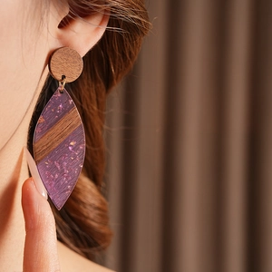 Gros plan de boucles d'oreilles en bois avec pendentifs en résine violette et feuilles d'or