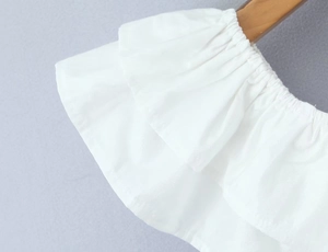 Detailed macro view of white tiered ruffles and elastic cuffs on a woven cotton top