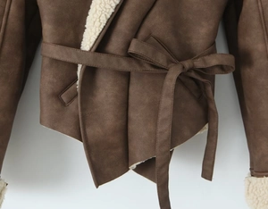 Dettaglio del fiocco in vita su giacca in camoscio marrone con fodera in pile color crema