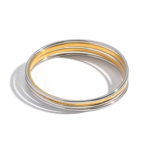 Detail of three stacked minimalist stainless steel bangles in mixed silver and gold