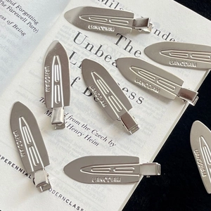 Artistic layout of silver metal no-crease hair clips on a white book page backdrop
