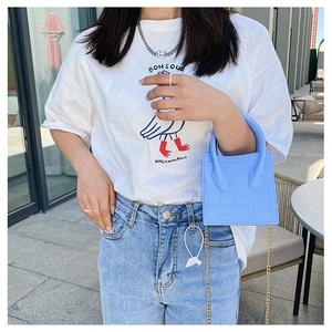 Blue crocodile pattern mini square handbag with chain strap shown in an outdoor cafe setting