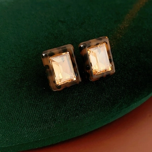 Macro shot of rectangular resin earrings with amber crystal and tortoiseshell frame
