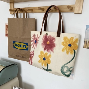 Detail of canvas tote bag with floral hand-painted pattern and brown leather handles
