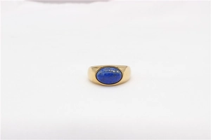 Detail shot of a minimalist gold ring featuring a broad band and oval blue gemstone