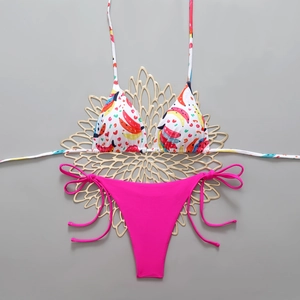 Close-up of tropical banana print bikini top and pink side-tie bottom on gold decor