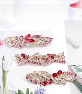 Detail of red rhinestone hair clips with floral and bow designs on gold alloy base