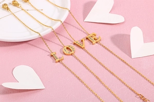Detail of gold chain bracelet featuring LOVE letter charms with sparkly rhinestones