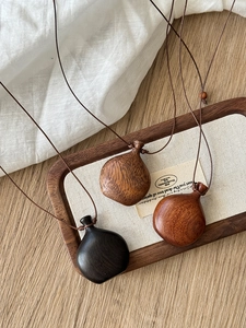 Detailed view of three wood gourd pendants in black, brown and reddish tones on ropes