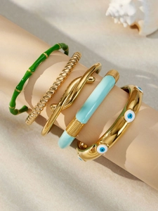 Dettaglio di cinque braccialetti impilabili placcati oro con malocchio e smalto in mostra