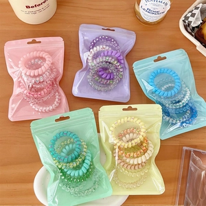 Detailed shot of five colorful gradient spiral hair ties in individual zip-lock bags