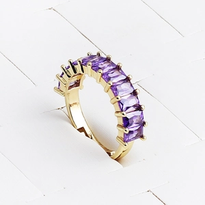 Macro shot of gold plated rectangular purple zircon ring set in a textured white background
