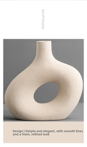 Macro shot of minimalist off-white ceramic ring vase featuring raw mineral speckled texture