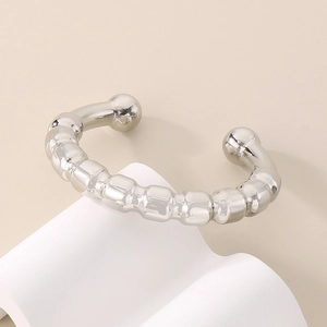 Detailed view of silver C-shaped cuff bracelet with beaded texture on white display