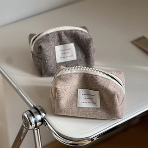 Detail of tweed herringbone makeup pouches with resin zippers and woven labels