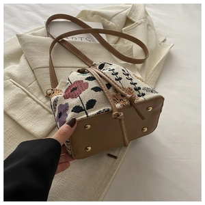 Detail view of ethnic jacquard bucket bag showing leather base and gold metal studs