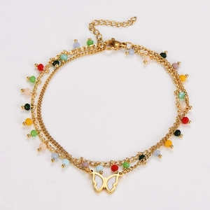Detail of layered gold ankle bracelet featuring colorful beads and butterfly charm