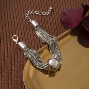 Close-up of multilayer silver chain bracelet with a central metal bead on a gold tray
