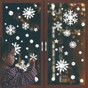 White Christmas snowflake window stickers featuring stars and dots on glass window with a child